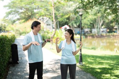 Üst düzey bir çift, açık havada egzersiz yaparken eğlenceli bir anı paylaşıyor. Birlikte hareket etmenin eğlenceli yanını gösteriyorlar..