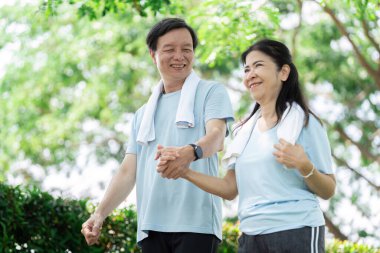 Üst düzey bir çift parkta el ele dolaşır, günlük yaşamlarında refahın ve arkadaşlığın önemini vurgular..