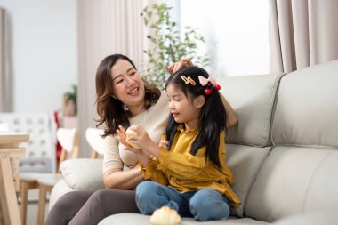 Bir anne kızıyla keyifli bir anı paylaşır. Oturma odasındaki rahat bir kanepede oynaşır..