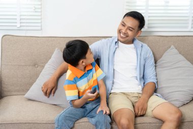 Bir baba ve oğul kanepede rahat bir anı paylaşıyor, oyun deneyimlerini tartışıyor ve rahat bir ortamda birbirlerine eşlik ederek eğleniyorlar..