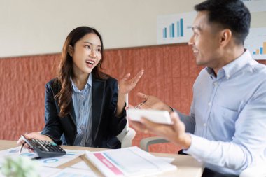 Ofisteki veri ve çizelgeleri incelerken finans stratejileri hakkında canlı bir tartışmaya giren bir erkek ve kadın..