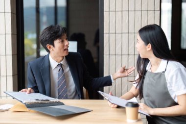 Modern bir ofiste proje stratejileri ve fikirleri tartışan iki profesyonel, işbirliğini teşvik ediyor.