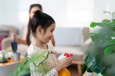 Neşeli bir kız çiçekleri sulamaktan, sorumluluk göstermekten ve doğa sevgisini göstermekten zevk alır. Bu arada annesi de rahat bir evde nezaret eder..