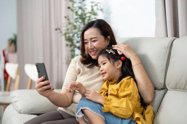 Bir anne ve kızı, yakın ilişkilerini sergilemek için birlikte akıllı telefona baktıklarında keyifli bir an yaşarlar..