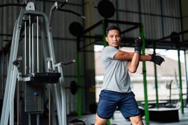 Dinamiklerini çalıştıran odaklanmış bir adam spor salonunda esnek ve güçlü bir antrenmana hazırlanır..