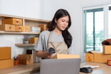 Küçük bir işletmedeki çalışkan bir çalışan yoğun bir nakliye bölgesindeki envanteri takip etmek için barkod tarayıcısı kullanıyor..