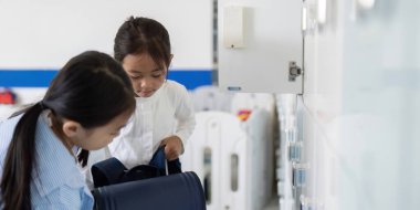 İki kız okul dolaplarında sırt çantalarını düzenliyor, takım çalışması ve gün için hazırlık yapıyorlar..