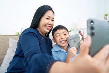 Bir anne ve oğul, seyahat planlarını ve aile bağlarını kutlamak için pasaportlarıyla selfie çekerken gülümserler..
