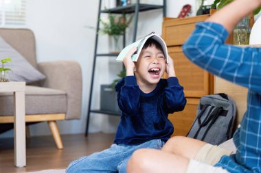 Mutlu bir çocuk bir arkadaşıyla oyun oynarken bir kitabı şapka olarak kullanarak güler. Çocukluk sevinci ve arkadaşlık kavramı.