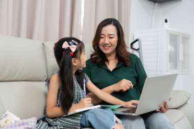 Bir anne, öğrenme ve teknolojiye olan sevgisini arttırmak için kızına dizüstü bilgisayarda okul ödevlerinde yardım eder..