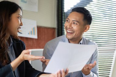 Bir erkek ve kadın proje detayları, ofiste takım çalışmasının teşvik edilmesi ve işbirliği hakkında animasyon bir konuşma paylaşıyorlar..