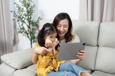 Bir anne ve kızı, rahatlıkla çevrili bir tabletten bir şey izlerken keyifli anlar yaşarlar..