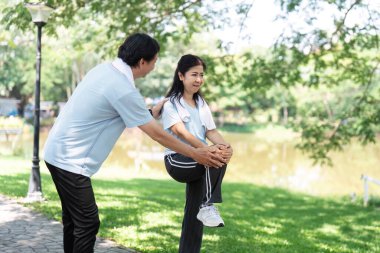 Yaşlı bir adam huzur parkında egzersiz rutininde bir kadına yardım ediyor. Kıdemli fitness ve aktif yaşam tarzını vurguluyor..