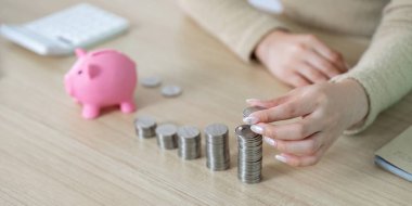 Bir kadın titizlikle kumbarasının yanına para istifliyor, finansal organizasyon ve tasarrufa olan bağlılığını vurguluyor..
