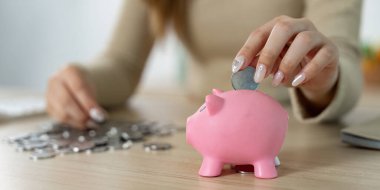 Bir kadın, kumbarasına madeni para ekleyerek para biriktirmeye odaklanır. Finansal isteklerini sembolize eder..