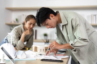 İki mimar, işbirlikçi bir çalışma alanında sürdürülebilir yapı planları ve modeller oluşturmaya derinden odaklanmıştır..