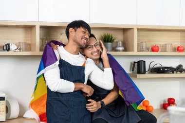 Gökkuşağı bayrağına sarılmış iki adam, aşklarını ve kapsallığını kutlamak için mutfaklarında hassas bir anı paylaşıyorlar..