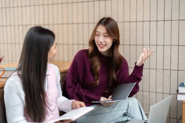 Bir çalışma alanında, iki arkadaş okul ödevleri hakkında verimli bir tartışmaya giriştiler, yeni dönem için hazırlanırken fikir ve notlar alışverişinde bulundular..