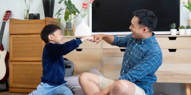 Neşeli bir baba ve oğul, keyifli bir anı paylaşır, gülümseme ve kahkahalarla birlikte, samimi bir oturma odasında öğrenirler..