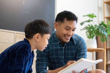 Bir baba ve oğul birlikte hoş bir okuma anını paylaşıyor, kitap sevgisi besliyor ve sıcak bir evde öğreniyor..