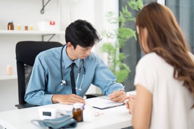 Bir doktor hasta ziyareti sırasında, sağlık hizmetlerinde kapsamlı belgelerin önemini vurgulayan notlar yazar..