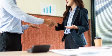 Modern ofis ortamında işbirliği ve ortaklığı temsil eden başarılı bir tokalaşmayı kutlayan iki iş adamı..