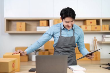 Odaklanmış bir girişimci, çağdaş bir ofis ortamında sevkiyat, verimlilik ve organizasyon için paketler hazırlar.