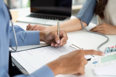 Bir sağlık uzmanı, klinik ortamda bir hastaya danışmanlık yaparken not alır..