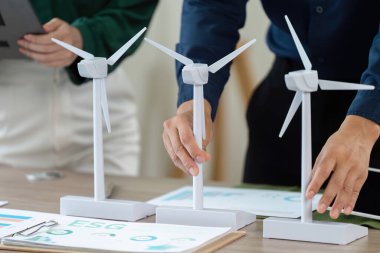 Sürdürülebilirlik odaklı ESG planlama oturumu sırasında yenilenebilir enerji modellerini analiz etmek için birlikte çalışan profesyoneller.