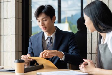 Gösterişli bir ofis ortamında önemli belgeleri incelerken müşteriye güncelleme sunan bir iş adamı.