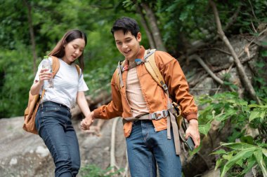 Bereketli yeşil bir ormanda yürüyüş yapan bir çift kayalık arazide gezinirken bir anlık bağlantıyı paylaşıyor..