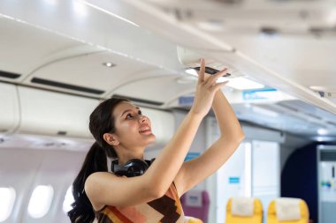 Gülümseyen bir gezgin çantasına ulaşır ve bir uçağın üst kompartımanında seyahat kolaylığını gösterir..