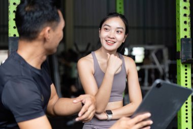 Spor salonundaki bir erkek ve kadın arasında keyifli bir sohbet, spor için sağlık tavsiyeleri ve planlarını paylaşmak..