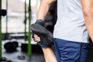 Spor salonunda bacak esneme hareketi yapan bir adam yoğun bir antrenmana hazırlanıyor. Forma ve sağlığa odaklan..