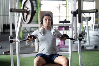 Bir fitness merkezinde müzik dinlerken makinede göğüs presi yapan kararlı bir adam..