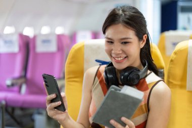 Neşeli bir gezgin uçakta otururken akıllı telefonuyla meşgul olur ve uçuş deneyiminin tadını çıkarır..