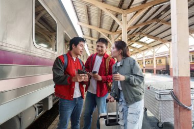 Arkadaşlar, bir tren istasyonunda planlarını tartışırken ve kahve içerken genç arkadaşlıkları yansıtıyorlar..