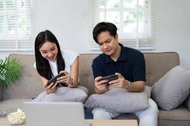 Bir çift kanepede oyun oynamaktan zevk alıyor. Rekabetçi ruhlarını ve kahkahalarını rahat bir ev ortamında sergiliyorlar..