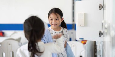 İki kız, okul dolaplarının yanında, arkadaşlığı ve okula dönmenin heyecanını simgeleyen neşeli bir anı paylaşıyor..