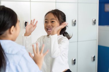 Okulun dolaplarında iki genç kız, yeni okul yılına neşe ve heyecan katarak neşeli bir anı paylaşıyor..