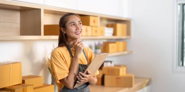 Düşünceli bir girişimci, lojistiği yönetirken ve parlak bir çalışma alanındaki paketleri denetlerken bir sonraki adımlarını düşünür..