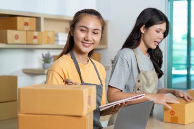 E-ticaret siparişlerini yönetmek için birlikte çalışan iki girişimci, ambalaj ve lojistik alanında takım çalışması sergiliyor.