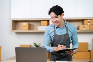 Gülümseyen bir girişimci envanter verilerini bir dizüstü bilgisayarda inceleyerek, çağdaş bir çalışma alanında etkili bir yönetimi vurguluyor.