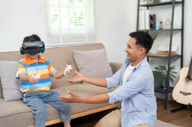 Babası onunla uğraşırken genç bir çocuk sanal gerçeklik oyununa daldı. Modern aile eğlencesi sergiliyordu..