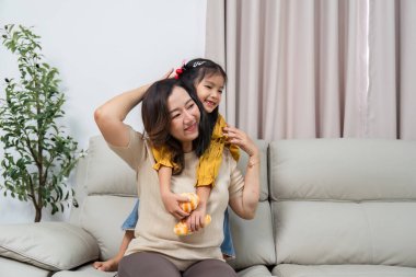 Bir anne, kızı neşeyle sırtüstü oturup neşeli ilişkilerini rahat bir ortamda vurgularken güler..