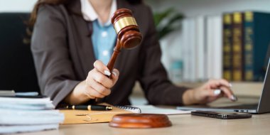 Çağdaş bir ofiste dizüstü bilgisayardaki görevleri yönetirken elinde tokmakla otoritesini gösteren bir hukuk uzmanı..