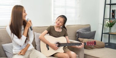 Bir anne ve kızı birlikte şarkı söyleyerek neşeli bir anı paylaşıyor, müzik yoluyla aile bağlarının önemini vurguluyor..