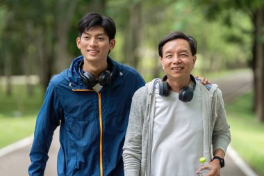 Neşeli bir baba ve oğul parkta yan yana yürürler, dışarıdaki etkinliklerle aile ve refahı somutlaştırırlar..