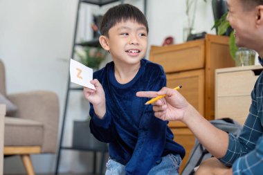 Bir baba ve oğul, interaktif oyun ve kahkahalarla öğrenmeyi geliştirmek için bilgi kartları kullanarak neşeli bir anı paylaşırlar..