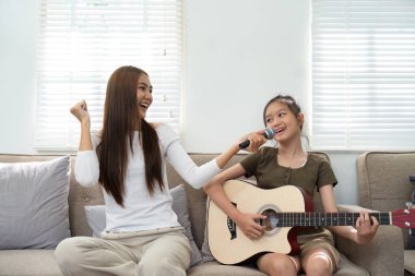 Bir anne ve kızı, müzik bağlarını ve mutluluklarını sergileyerek, birlikte şarkı söyleyerek neşeli bir anı paylaşırlar..